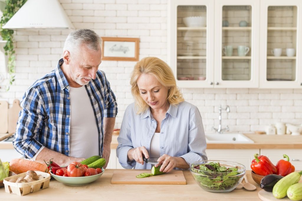 smiling-man-looking-her-wife-cutting-cucumber-with-knife-table-kitchen.jpg